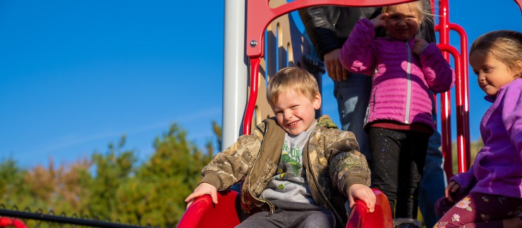Cardinal CSD preschool student about to go down the slide on the playground.