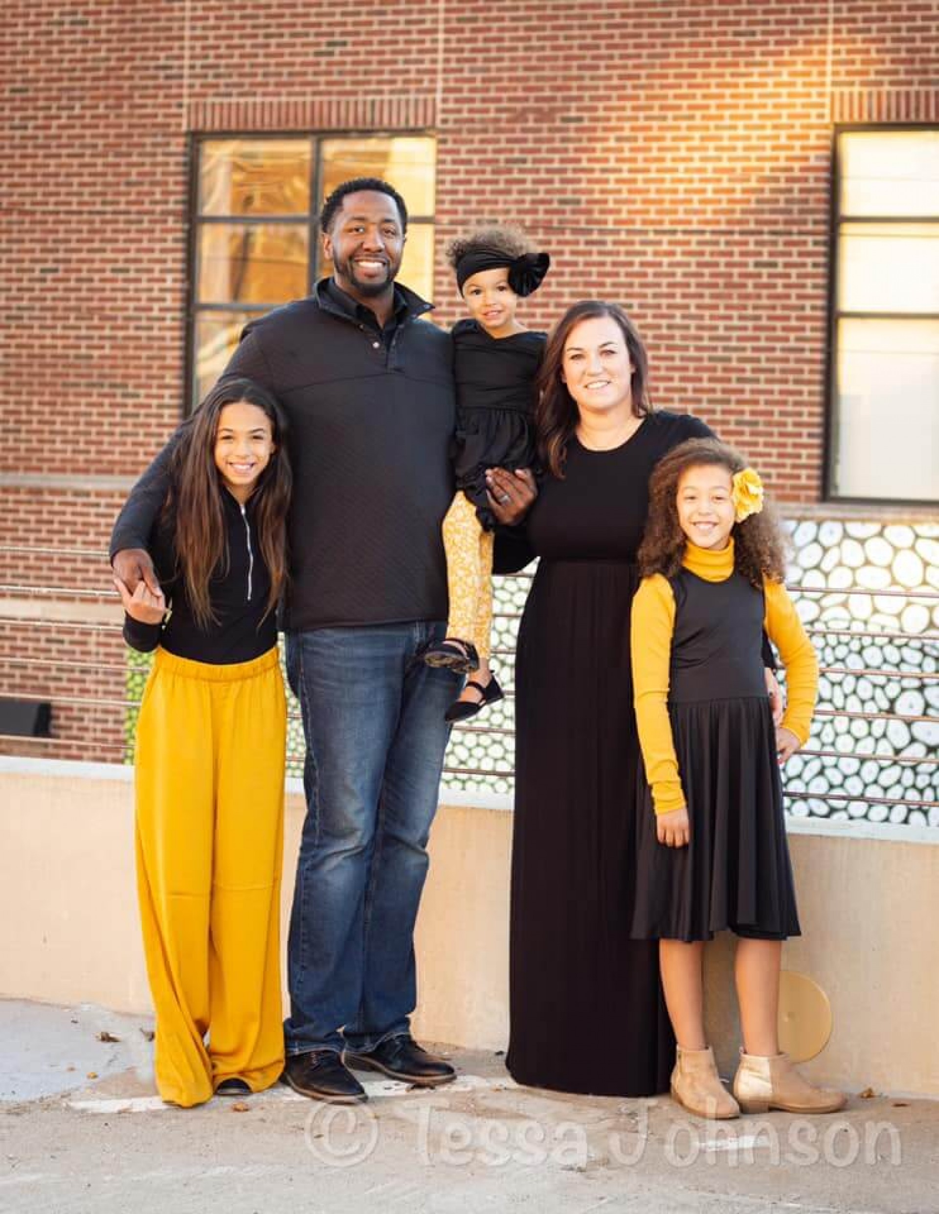 New Football Coach Rich Mayson and his wife Kristin and three daughters posing for a family photo.