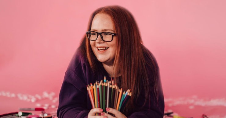 Paityn Mellott poses with her favorite pens and colored pencils against a bubble-gum-pink backdrop.