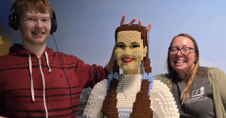 Daena Peterman poses with a child next to a life-size replica of Dorothy from the Wizard of Oz, made out of Lego bricks.